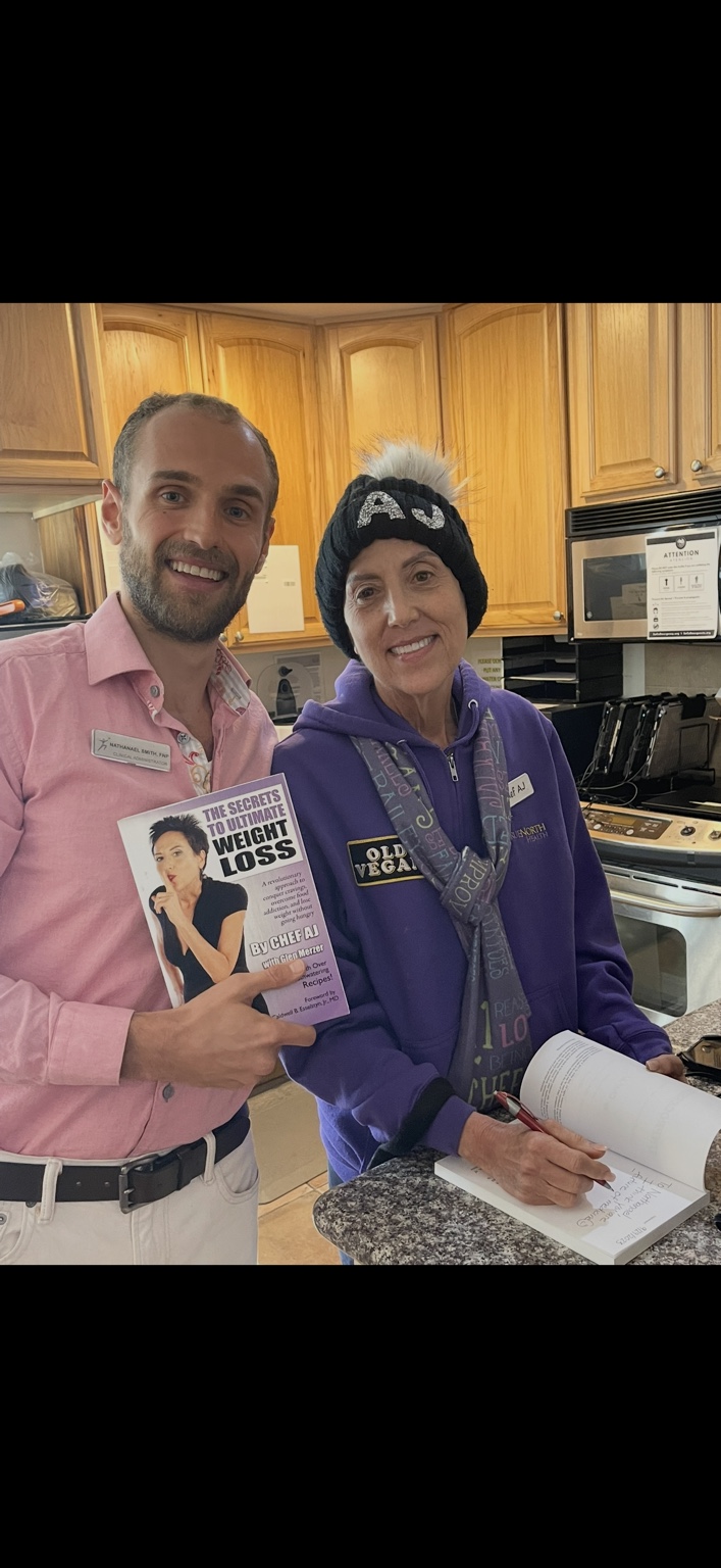 Nathanael standing with Chef AJ while holding The Secrets to Ultimate Weight Loss.