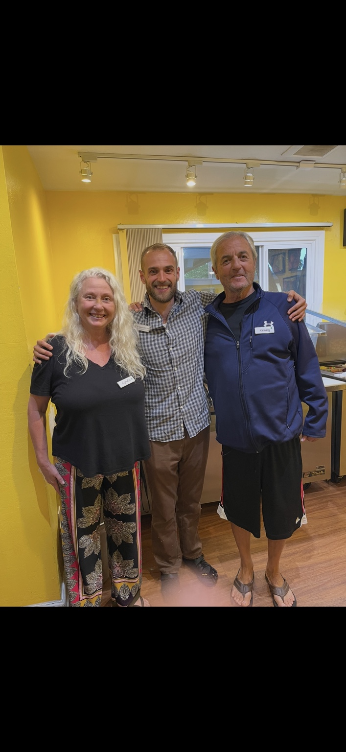 Nathanael standing between two smiling adults at TrueNorth Health Center.