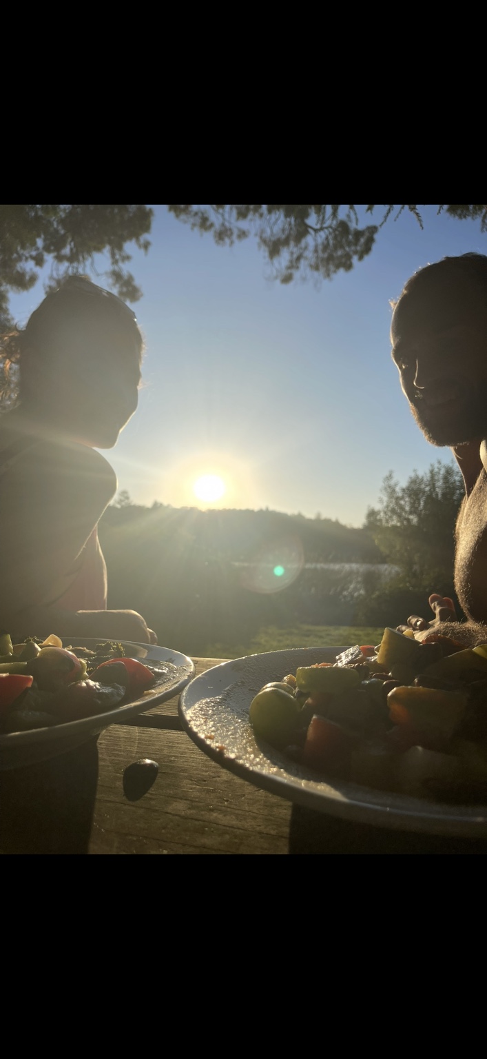 Two people sharing a colorful plant-based meal outdoors at sunset.