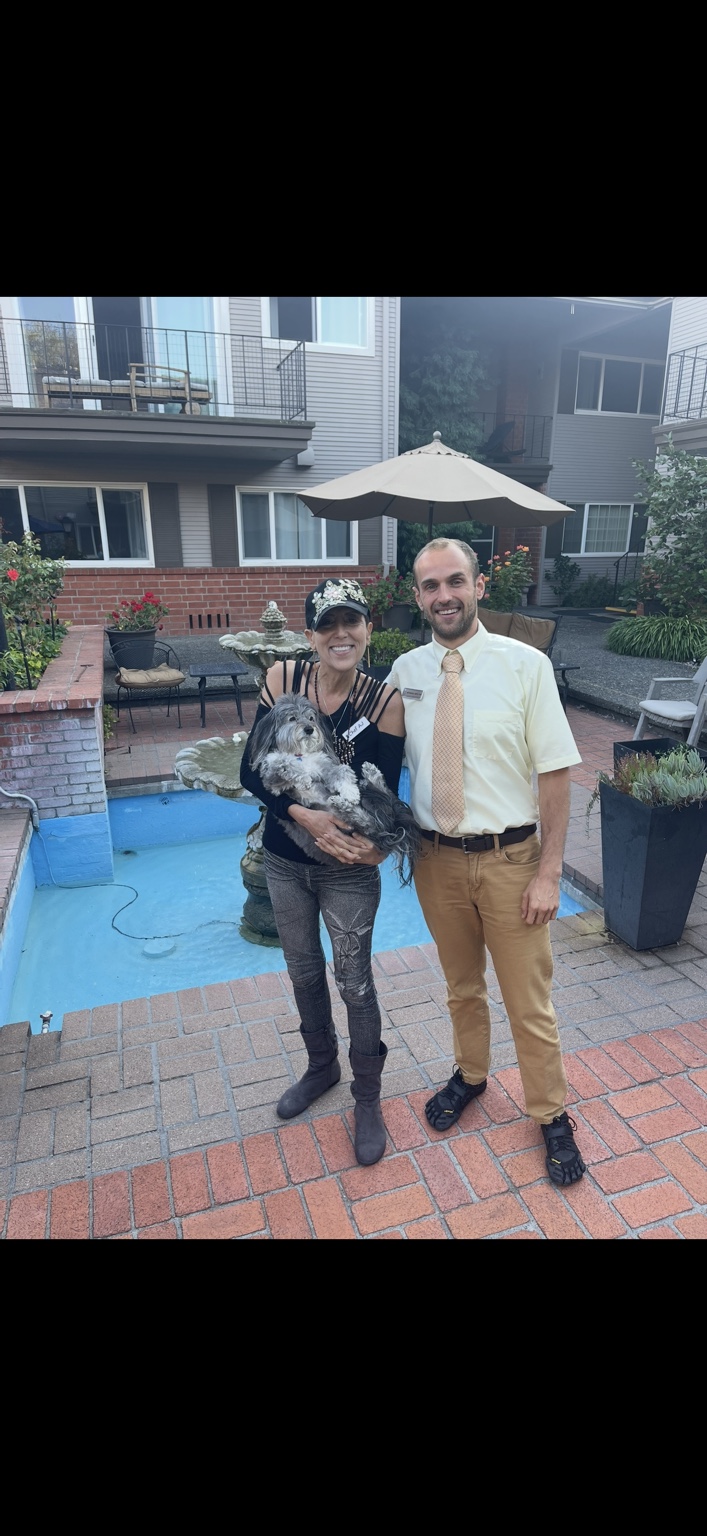 Nathanael standing outdoors with Chef AJ as she holds her dog Bailey.