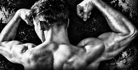 Black-and-white photograph of Kenneth Smith flexing both arms